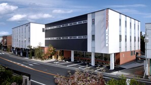 Un edificio moderno con techo plano, ventanas amplias y un estacionamiento.
