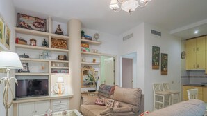Ein Wohnzimmer mit einer Couch, einem Fernseher und Regalen mit verschiedenen Gegenständen.