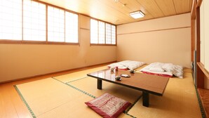 Um espaço com tatames, uma mesa baixa, almofadas e um futon.