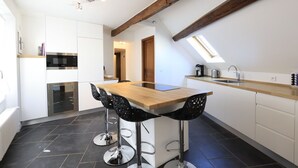 A modern kitchen with a wooden island, black bar stools, and a built-in oven. - Le Hoche Les Demoiselles in Versailles 1 minute from the Château de Versailles (Versailles)