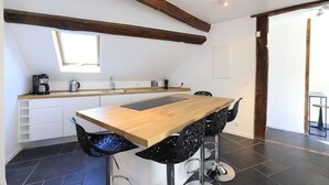 A modern kitchen with a wooden countertop, black bar stools, and a skylight. - Le Hoche Les Demoiselles in Versailles 1 minute from the Château de Versailles (Versailles)