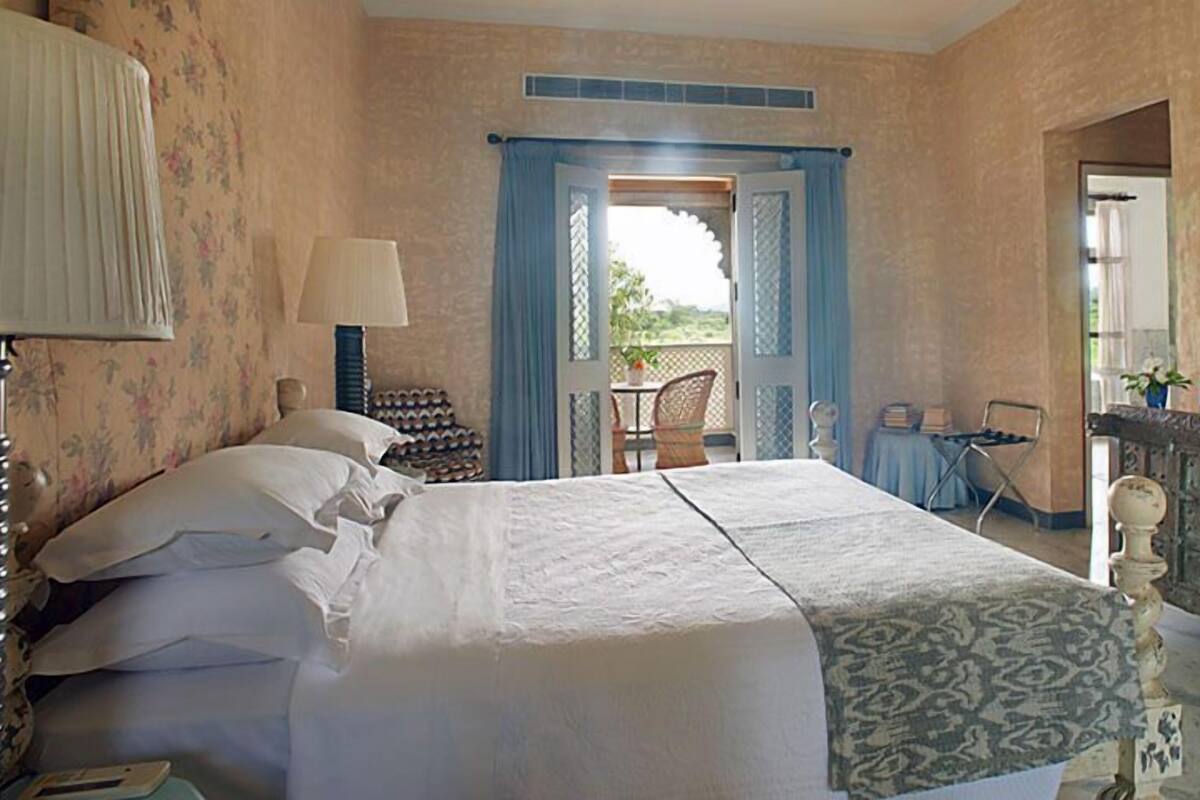 Un dormitorio con una cama, un aparador, una silla y vistas a través de una puerta.