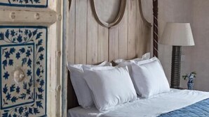 Un dormitorio con cama con dosel, ropa de cama blanca y colcha azul.