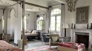 Una habitación amplia con una cama grande, una silla, una mesita y una chimenea.