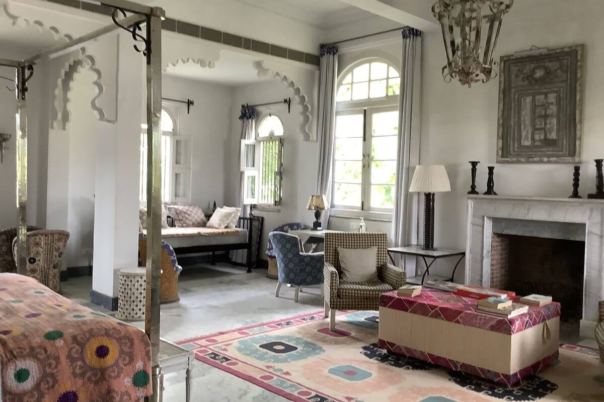 Una habitación amplia con una cama grande, una silla, una mesita y una chimenea.
