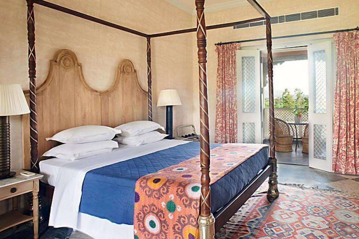 Una cama con dosel con un edredón azul y blanco, un cabecero de madera y una alfombra estampada.