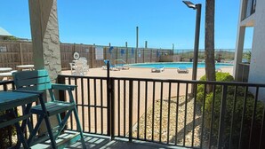 A pool area with lounge chairs and a wooden fence. - Moondrifter 105 (Panama City Beach)