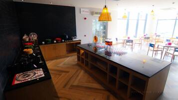 A modern restaurant interior with a central island, wooden flooring, and pendant lighting.
