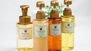 Four bottles of shower products with labels, arranged on a white surface with green plants at the bottom. - Lucky Yotsuki (Tokyo)