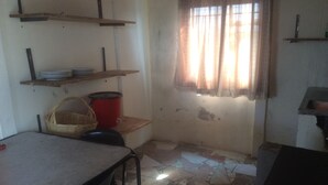 A room with a table, chairs, shelves, a red pot, and a window with curtains. - NHAKA Savaal - cottage DETROIT (Harare)