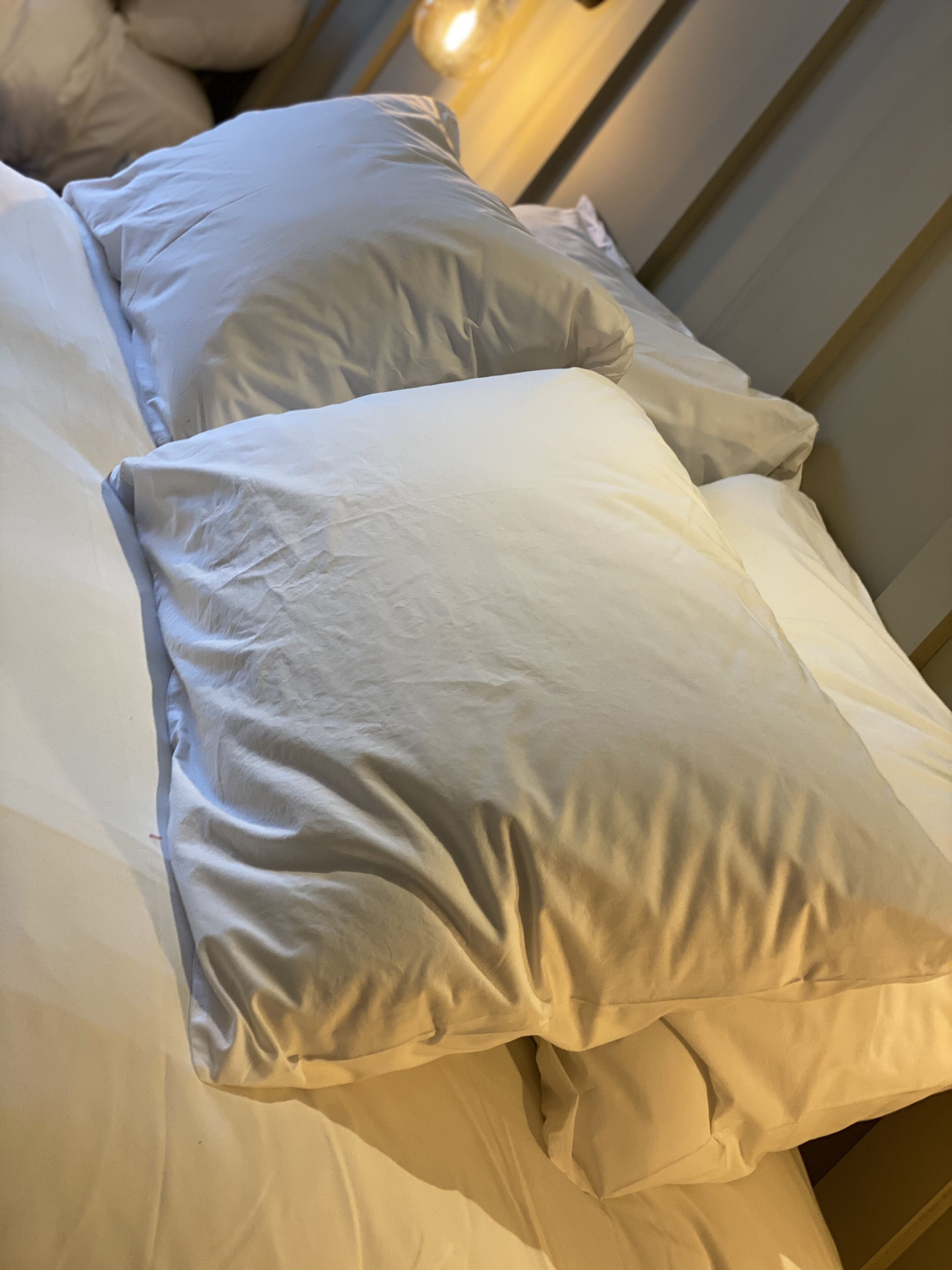 A bed with white linens and pillows.