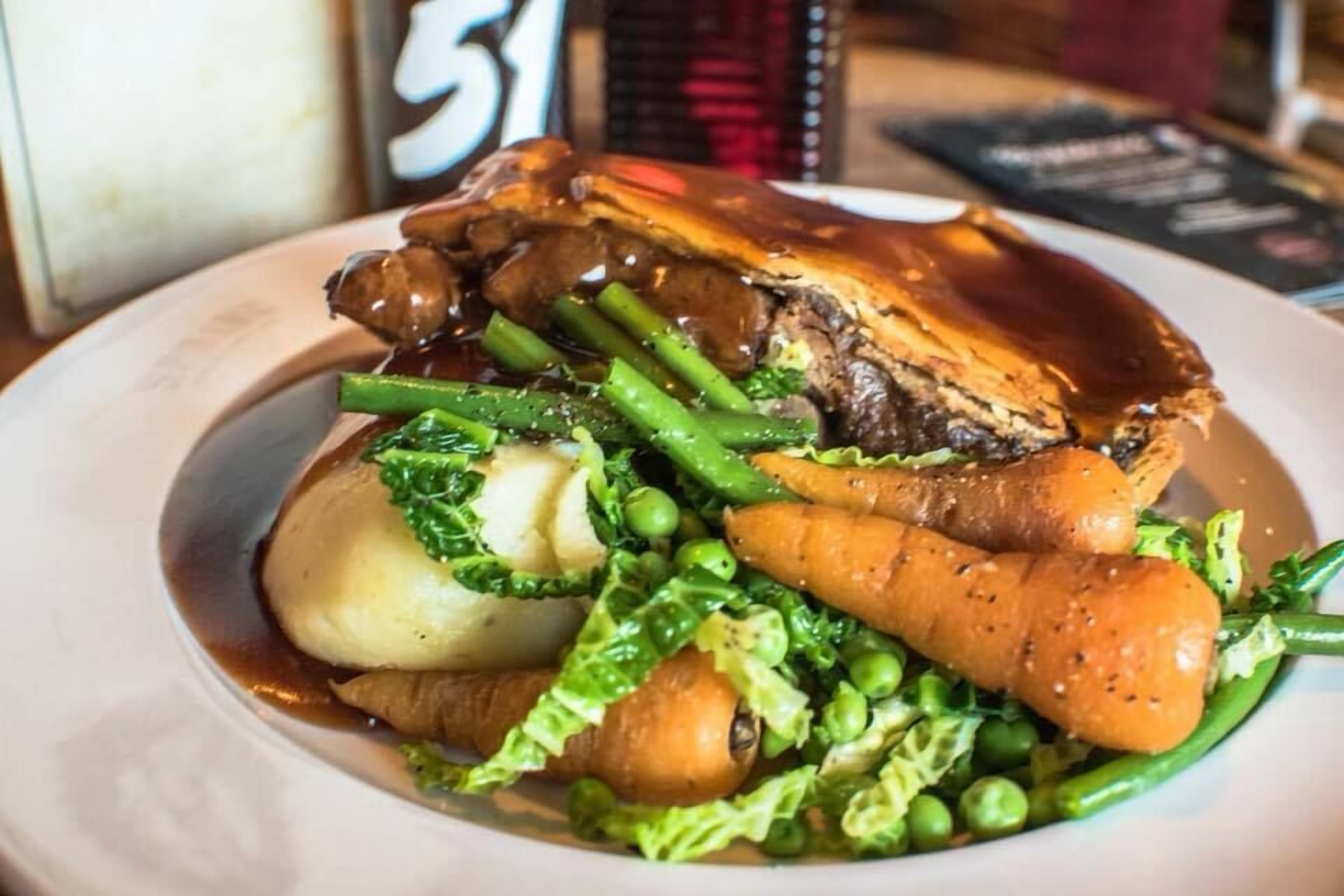 Un plato de comida con una variedad de verduras y un trozo de carne, posiblemente asada.