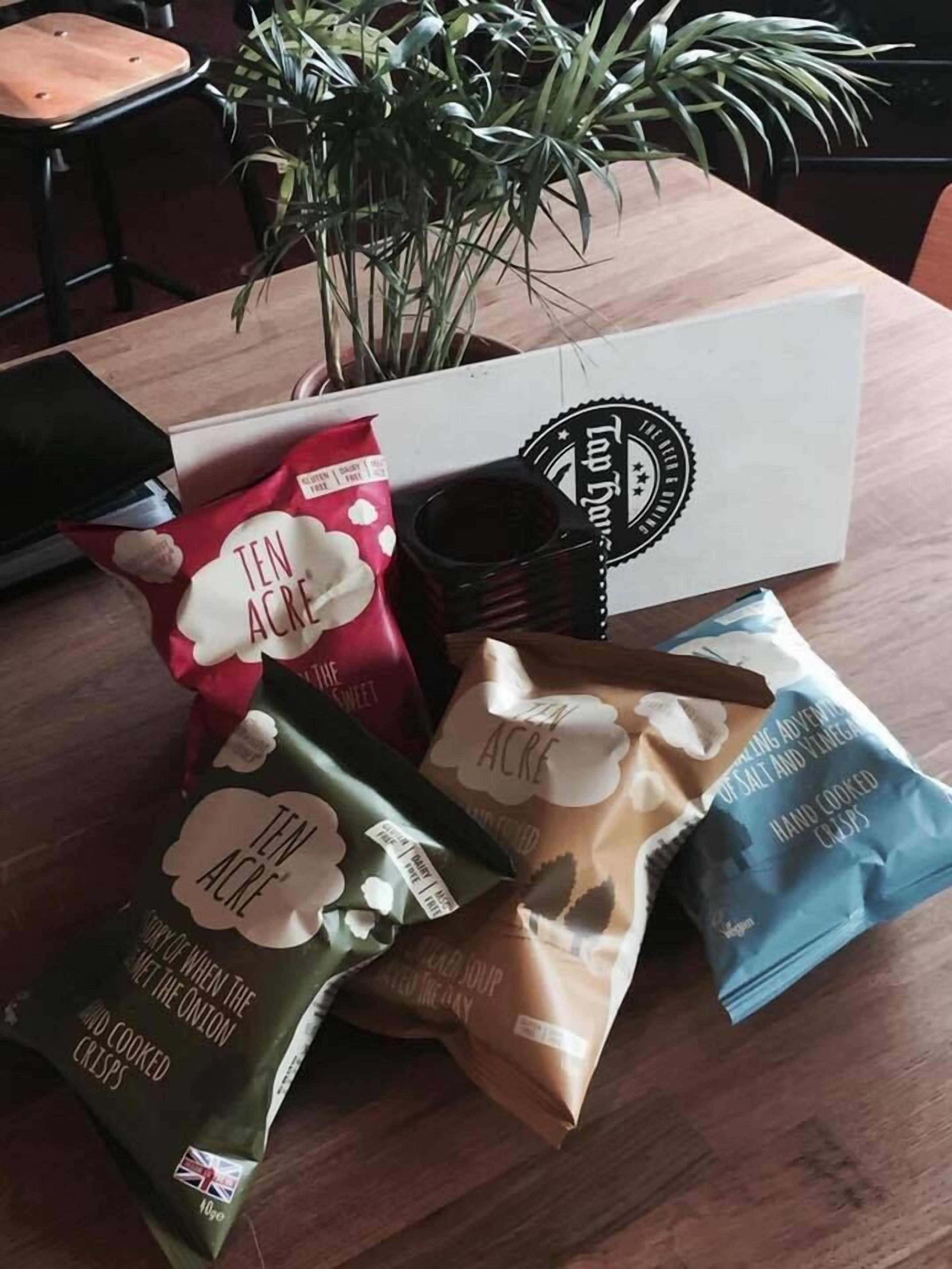 Una mesa con diferentes alimentos, incluyendo bolsas de patatas fritas y una caja con un logotipo.