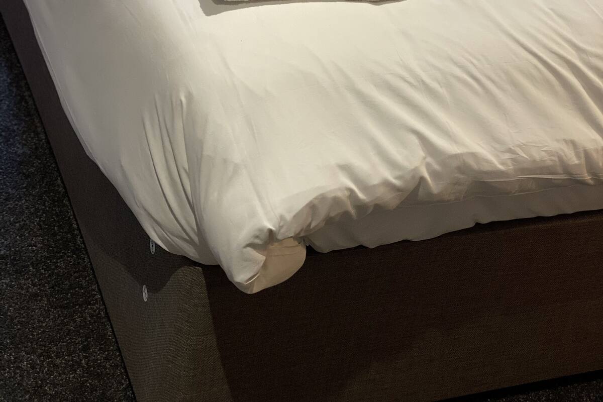A neatly made bed with white linens and folded towels.