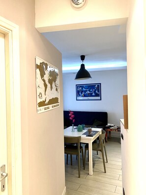 A narrow hallway with a dining area featuring a table, chairs, and a world map on the wall.