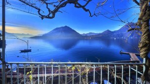 Una vista panorámica de un lago con montañas al fondo, un muelle y una barandilla en primer plano.