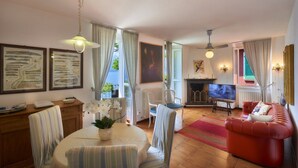 Una sala de estar con una mesa de comedor, sillas, un sofá rojo, una chimenea y un televisor.