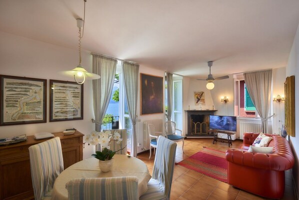 A living room with a dining table, chairs, a red sofa, a fireplace, and a television.
