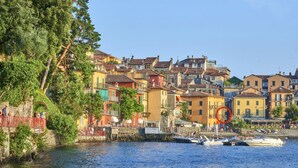 A waterfront town with colorful buildings, a stone wall, and boats docked at the pier.
