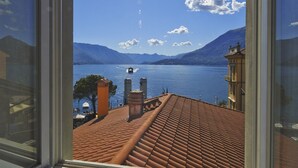 Vista de un lago con montañas al fondo y un edificio con techo de tejas en primer plano.