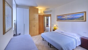 Habitación de hotel con dos camas, un armario, un cuadro en la pared y una lámpara en la mesita de noche.