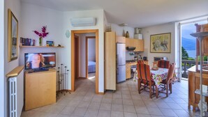 Un espacio habitable compacto con cocina, comedor y televisor sobre un mueble de madera.