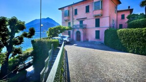 A pink building with a paved driveway and a car parked in front. - Casa Royal beautiful Garden (Varenna)