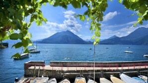 A marina with boats docked, a pier, and mountains in the background. - Casa Pergola on the lakeshore (Varenna)
