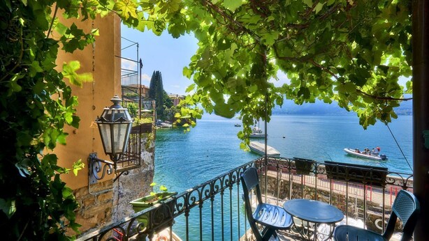 A balcony with a view of the sea, a table, chairs, and a lamp. - Casa Pergola on the lakeshore (Varenna)