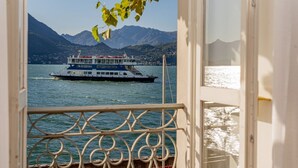 A view from a balcony with a metal railing, overlooking a lake with a boat and mountains in the background. - Casa Pergola on the lakeshore (Varenna)
