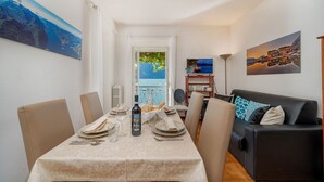 A dining area with a table set for two, a sofa, and a TV in the background. - Casa Pergola on the lakeshore (Varenna)