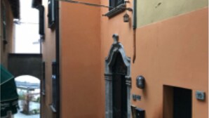 A narrow hallway with an ornate door and a small window. - Casa Riva on the lakeshore (Varenna)