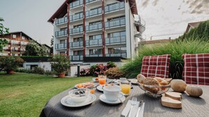 A breakfast table set outdoors with a view of a multi-story building with balconies. - Pension- Hotel Maximilian (Bad Fuessing)