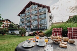 Mesa de desayuno al aire libre con vista a un edificio de varios pisos con balcones.