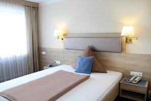 A hotel room with a bed, bedside lamps, a nightstand, a telephone, and a window with curtains. - Pension- Hotel Maximilian (Bad Fuessing)