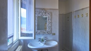 A bathroom with a double sink, a large ornate mirror, and a glass shower enclosure. - Wonderful Casa Veranda (Varenna)