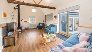 A spacious living room with a fireplace, a sofa, a coffee table, and a television. - Spacious barn, seals, seaside walks and Broads National Park (Great Yarmouth)