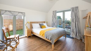 A bedroom with a bed, wooden floor, a chair, a desk, and a window with curtains. - Spacious barn, seals, seaside walks and Broads National Park (Great Yarmouth)