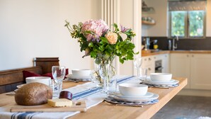 A dining table set with plates, bowls, glasses, and a loaf of bread. - Spacious barn, seals, seaside walks and Broads National Park (Great Yarmouth)