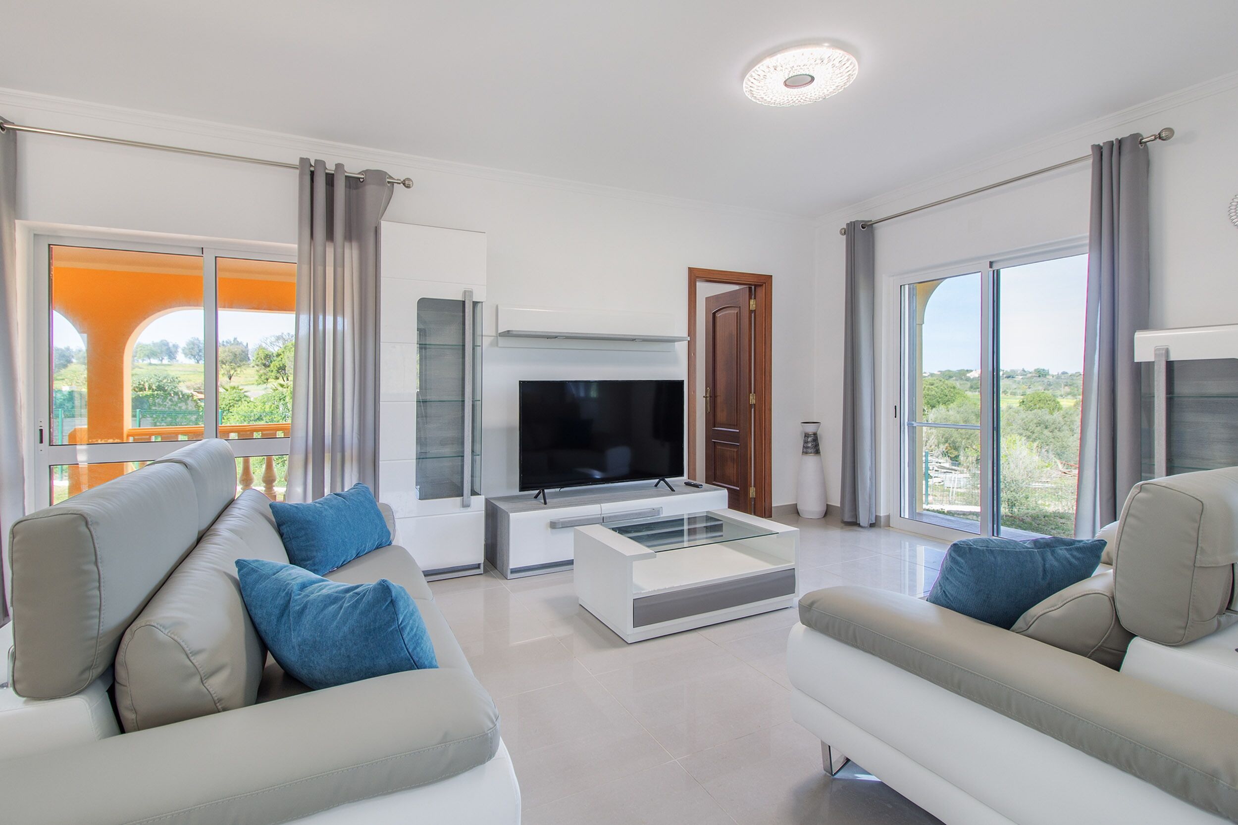 A modern living room with a flat-screen TV, two sofas, and a coffee table.