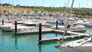 A marina with multiple boats docked, a dock with a boat ramp, and buildings in the background. - Villa in Alporchinhos (Porches) within walking distance to the beach. (Porches)