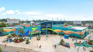 Un grand aquarium aux couleurs vives, doté d’une entrée imposante et entouré d’autres attractions.