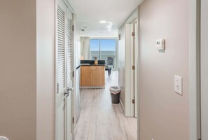 A hallway leading to a kitchen with a view of the sky through a large window. - Direct Oceanfront Remodeled King 2BR,Amazing Views (Myrtle Beach)