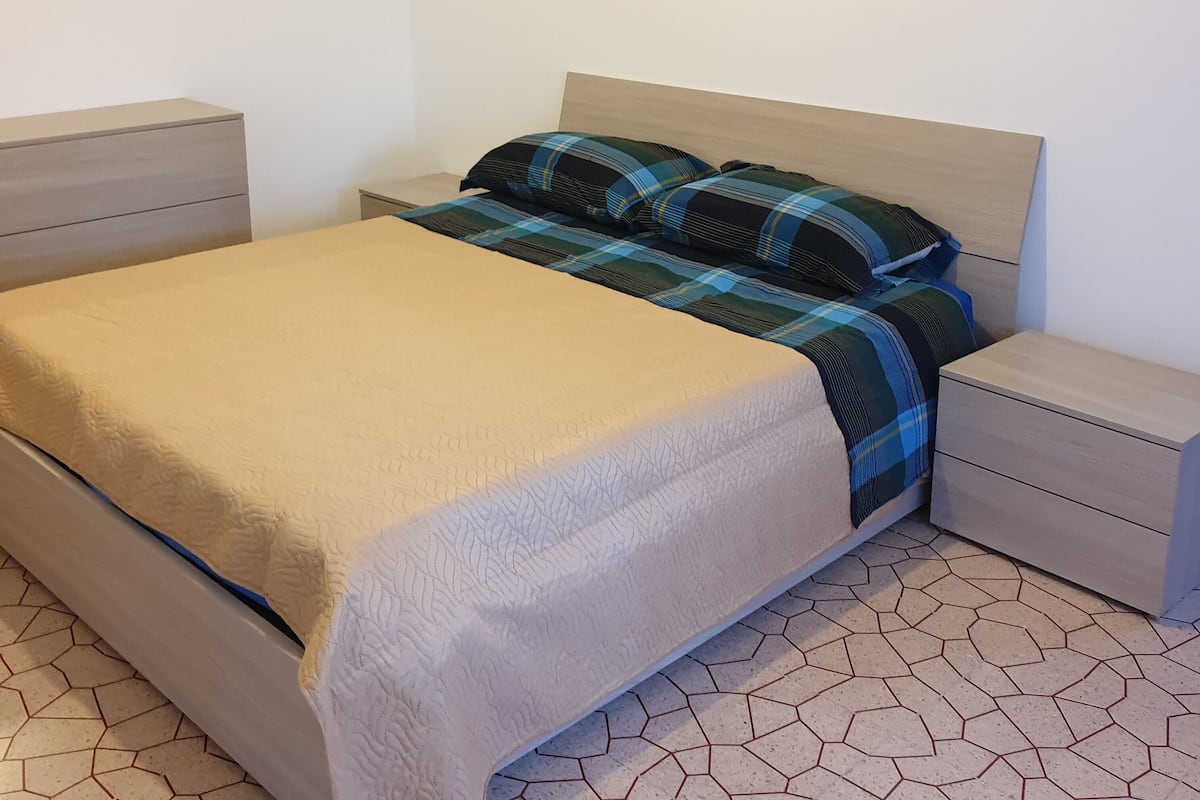 Une chambre à coucher comprenant un lit, deux tables de chevet et une œuvre d’art accrochée au mur.