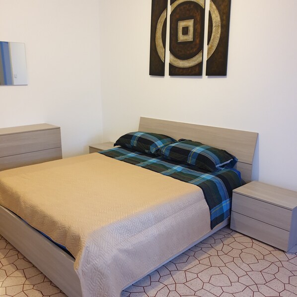 Un dormitorio con una cama, dos mesitas de noche y una obra de arte colgada en la pared.
