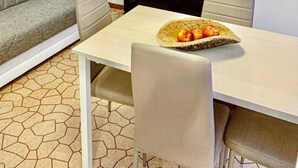 A modern living room with a sofa, a dining table with chairs, a TV, and a wall art piece. - Appartamenti Viale Italia (Sassari)