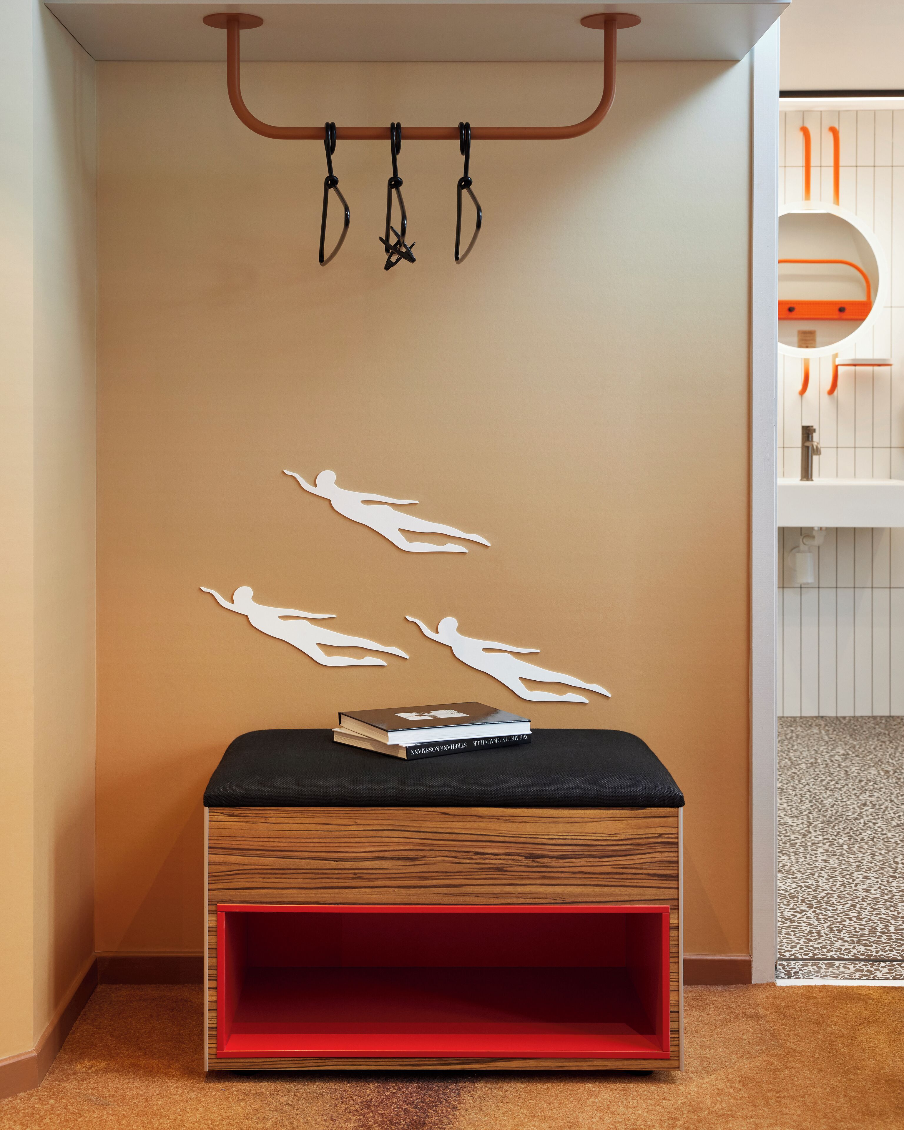 A room with a wooden bench, a hanging coat rack, and a wall with paper cutouts of people.