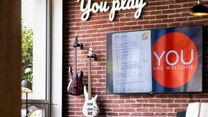 Una habitación con pared de ladrillo, un piano, un sofá y guitarras.