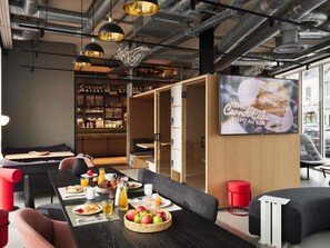A modern dining area with a long table, chairs, and a bar with shelves of bottles.