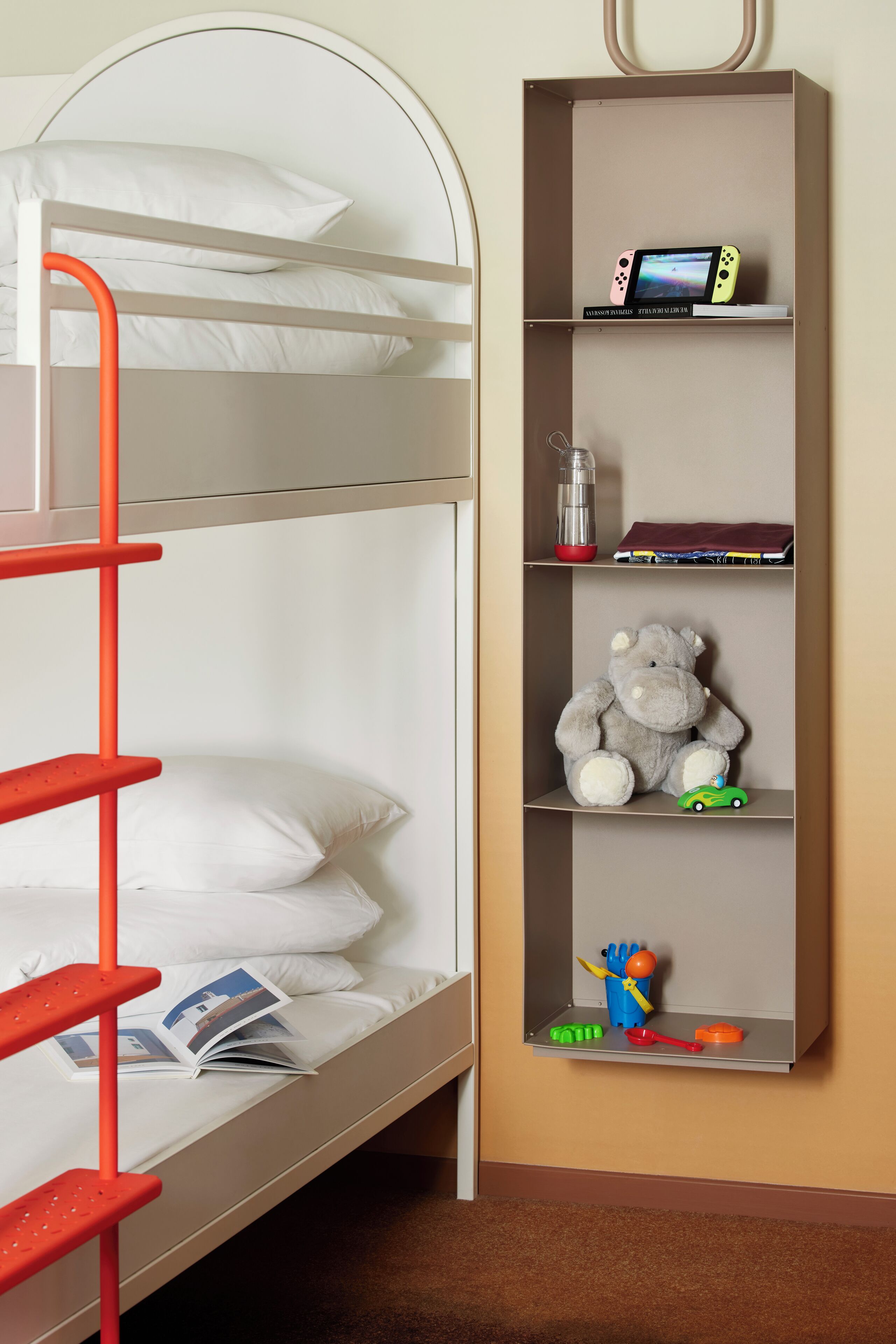 A bunk bed with a red ladder, a bookshelf with a teddy bear, and a toy car.